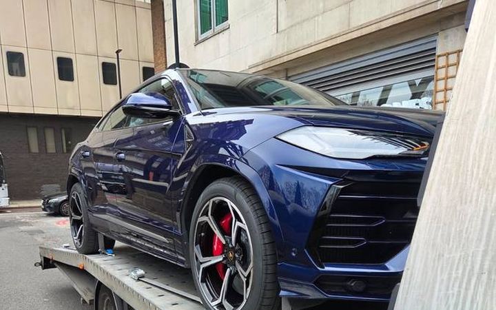 Blue Lamborghini Urus luxury SUV on recovery truck flatbed