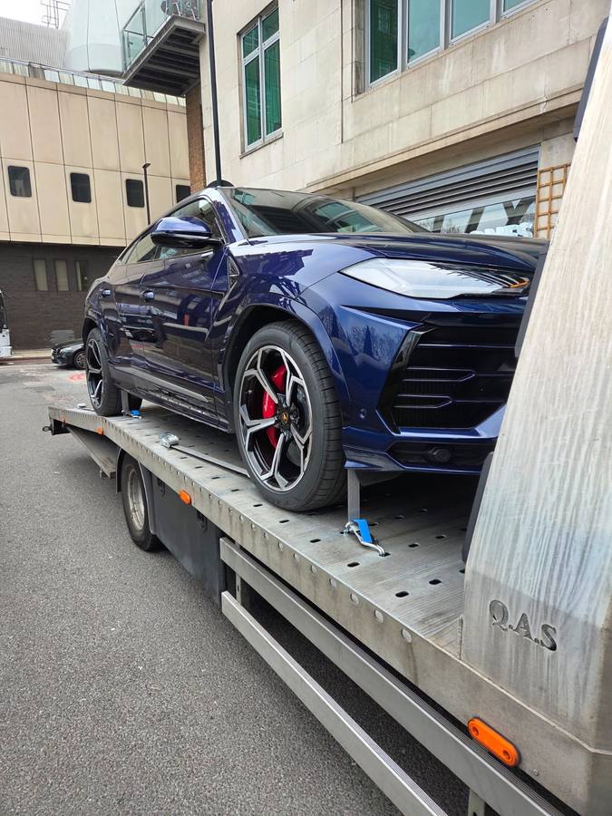 Blue Lamborghini Urus luxury SUV on recovery truck flatbed