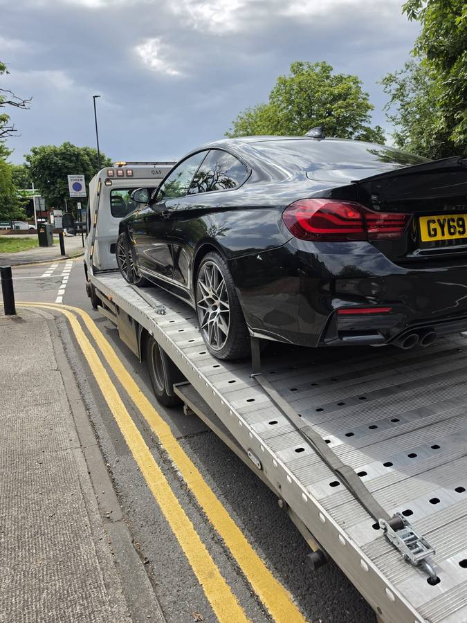 Black BMW 4-series loaded on recovery flatbed at street parking location