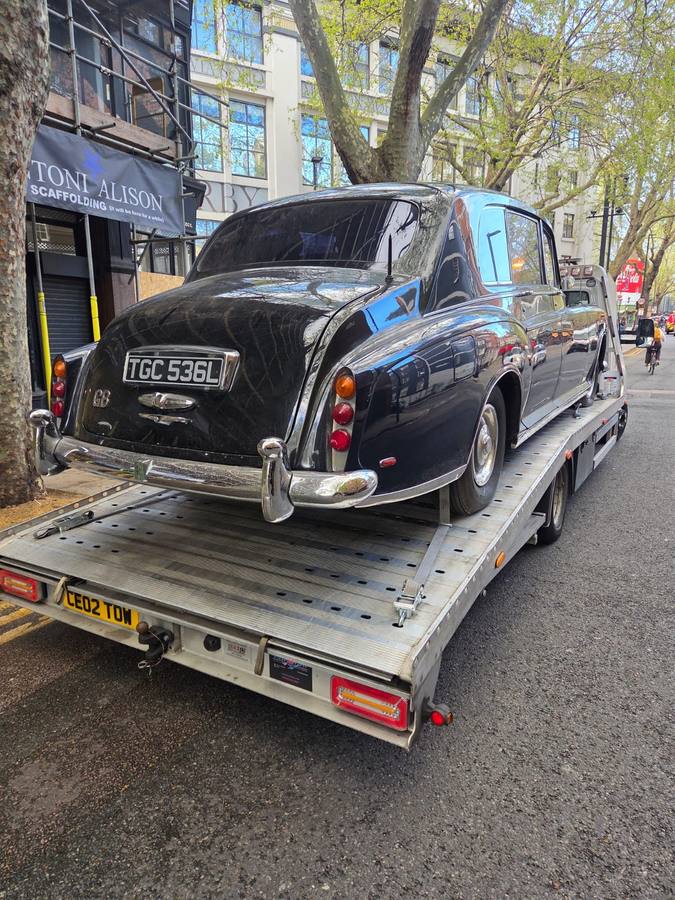 Black vintage Jaguar car on recovery flatbed in busy London street