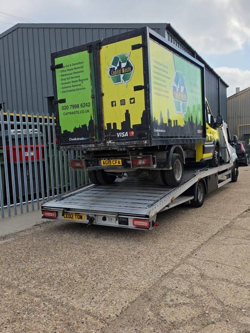 Black and yellow branded commercial truck loaded on recovery flatbed